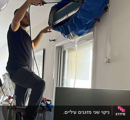 טכנאי מתקין מזגן עם כיסוי כחול על סולם